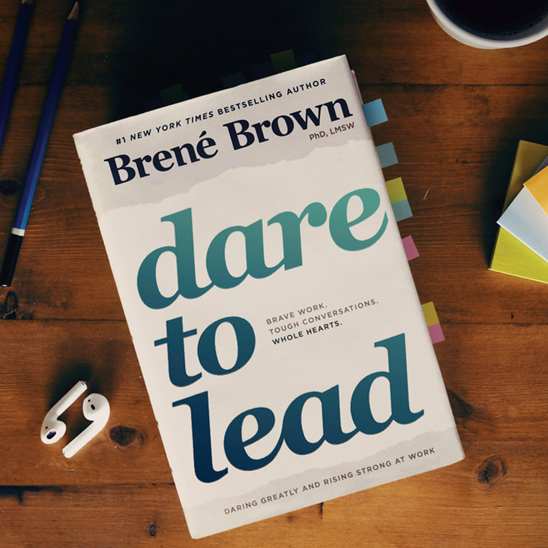 Brene Brown Dare to Lead book with airpods a pen and a pad of paper